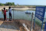 Dua Anak melihat embung yang airnya menurun di Desa Kodik, Pamekasan Jawa Timur, Rabu (7/10/2020). Embung seluas 5 hektare dengan pola penyaringan Water Treatment Plant (WTP) yang diharapkan mampu memenuhi kebutuhan air konsumsi untuk warga ditiga kecamatan itu, airnya menyusut sekitar 35 persen, akibat kemarau. Antara Jatim/Saiful Bahri/zk