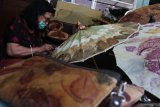 Perajin membuat payung di Surabaya, Jawa Timur, Senin (12/10/2020). Produk kerajinan dompet, tas, kipas tangan dan payung berbahan baku dari kertas sak semen yang dihias dengan daun maupun bunga kering ataupun dihias dengan teknik 'ecoprint' maupun dengan teknik 'jumputan' tersebut dijual dengan harga Rp15 ribu sampai Rp750 ribu tergantung ukuran serta tingkat kesulitan. Antara Jatim/Didik/Zk