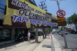 Warga berjalan di dekat spanduk yang terpasang di Jalan Embong Malang, Surabaya, Jawa Timur, Rabu (14/10/2020). Sejumlah spanduk yang terpasang di jalan protokol itu untuk mengajak warga menjaga kedamaian dan tidak melakukan perusakan saat berunjuk rasa. Antara Jatim/Didik/Zk