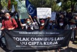 Pengunjuk rasa dari Solidaritas Aliansi Rakyat Pro Demokrasi (SANTI) meneriakkan yel-yel menolak Omnibus Law UU Cipta Kerja di Denpasar, Bali, Jumat (16/10/2020). Aksi tersebut mendesak DPRD Bali agar secara kelembagaan bersurat kepada DPR untuk membatalkan UU Cipta Kerja serta mengecam pernyataan sikap gubernur Bali yang setuju dengan UU Cipta Kerja. ANTARA FOTO/Nyoman Hendra Wibowo/nym.