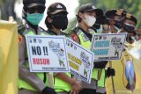 Polisi berjaga dengan membawa poster imbauan saat sejumlah buruh berunjuk rasa di depan gedung DPRD Jawa Timur, Surabaya, Jawa Timur, Kamis (22/10/2020). Massa buruh menyerukan 'Tolak dan Batalkan Undang-Undang Cipta Kerja'. Antara Jatim/Didik/Zk