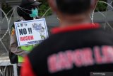Polisi berjaga dengan membawa poster imbauan saat sejumlah buruh berunjuk rasa di depan gedung DPRD Jawa Timur, Surabaya, Jawa Timur, Kamis (22/10/2020). Massa buruh menyerukan 'Tolak dan Batalkan Undang-Undang Cipta Kerja'. Antara Jatim/Didik/Zk
