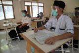 Pelajar menggunakan busana muslim memperingai hari santri mengikuti kegiatan belajar mengajar (KMB) tatap muka terbatas di SMA Negeri 2 Jombang, Jawa Timur, Kamis (22/10/2020). Pembelajaran tatap muka di sekolah tersebut menerapkan protokol kesehatan pencegahan penularan COVID-19 yang ketat dan per kelasnya hanya diikuti maksimal 15 siswa. Antara Jatim/Syaiful Arif/zk