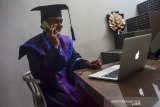 Wisudawan Universitas Galuh (Unigal) Luki Lukman mengikuti acara wisuda sarjana secara daring dari rumah di Imabanagara, Kabupaten Ciamis, Jawa Barat, Kamis (22/10/2020). Wisuda daring yang digelar dalam Sidang Terbuka Senat Universitas Galuh Ciamis itu menggunakan aplikasi Zoom Meeting dan disiarkan secara langsung di platform Youtube, sebagai implementasi kebijakan physical distancing untuk meminimalisasi penyebaran wabah COVID-19. ANTARA JABAR/Adeng Bustomi/agr