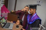 Orang tua dari wisudawan Universitas Galuh (Unigal) Luki Lukman memindahkan tali toga saat mengikuti acara wisuda sarjana secara daring dari rumah di Imabanagara, Kabupaten Ciamis, Jawa Barat, Kamis (22/10/2020). Wisuda daring yang digelar dalam Sidang Terbuka Senat Universitas Galuh Ciamis itu menggunakan aplikasi Zoom Meeting dan disiarkan secara langsung di platform Youtube, sebagai implementasi kebijakan physical distancing untuk meminimalisasi penyebaran wabah COVID-19. ANTARA JABAR/Adeng Bustomi/agr