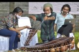 Perajin Neo Akbar (tengah) menunjukkan proses pembuatan alat musik tradisional buatannya saat kegiatan Lokakarya Produksi dan Distribusi Alat Musik Tradisional di kawasan Desa Sangketan, Tabanan, Bali, Sabtu (24/10/2020). Kegiatan tersebut diselenggarakan untuk mengenalkan dan membahas proses produksi hingga distribusi berbagai jenis alat musik tradisional sebagai upaya mendukung pengembangan ekonomi kreatif bagi kreator dan produsen alat musik tradisional. ANTARA FOTO/Fikri Yusuf/nym