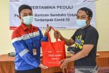 Supervisor HSSE Ardi Hutri Prayitno (kiri) memberikan paket sembako kepada warga saat kegiatan Pertamina peduli di kantor Kelurahan Sukanagara, Kota Tasikmalaya, Jawa Barat, Senin (26/10/2020). Pertamina memberikan paket bantuan sembako bagi warga terdampak COVID-19 sekaligus peluncuran program Corporate Social Responsibility (CSR) pemberdayaan masyarakat berupa budidaya lele, bank sampah dan Sistem Infomasi Posyandu Terintegrasi (Sipter). ANTARA JABAR/Adeng Bustomi/agr