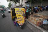 Warga mengantre untuk mendapatkan makanan secara gratis di gerobak makanan milik Setiyono di jalan Kedungsari, Surabaya, Jawa Timur, Selasa (27/10/2020). Aksi sosial pemberian makan gratis untuk semua orang sebanyak 100 porsi setiap hari tersebut guna membantu meringankan beban ekonomi masyarakat di tengah pandemi COVID-19. Antara Jatim/Moch Asim/zk.