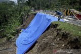 Warga melihat lokasi longsor di Desa Najaten, Cibalong, Kabupaten Garut, Jawa Barat, Jumat (30/10/2020). Sebagian badan jalan lintas selatan penghubung Garut-Tasikmalaya yang longsor tersebut sudah bisa dilalui kendaraan roda dua maupun roda empat yang akan berwisata menuju pantai selatan. ANTARA JABAR/Candra Yanuarsyah/agr.