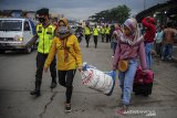 Anggota Kepolisian melintas di depan calon penumpang yang menunggu kedatangan bus menuju Jakarta di terminal bayangan Gerbang Tol Cileunyi, Kabupaten Bandung, Jawa Barat, Minggu (1/11/2020). Kepala Bagian Operasi Korps Lalu Lintas Polri Komisaris Besar Rudi Antariksawan mengatakan, puncak arus balik libur panjang cuti bersama menuju Jakarta di berbagai daerah akan terjadi pada Minggu (1/11/2020) malam ini. ANTARA JABAR/Raisan Al Farisi/agr