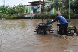 Seorang warga mendorong becak motor melintasi jalan yang terendam banjir di Kwadungan, Ngawi, Jawa Timur, Senin (2/11/2020). Banjir Sungai Madiun mengakibatkan sejumlah ruas jalan dan ratusan hektare sawah dengan tanaman padi siap panen di wilayah tersebut terendam. Antara Jatim/Siswowidodo/zk