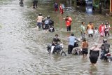 Pengendara sepeda motor menerobos jalan yang tergenang banjir di kawasan jalan raya Gempol, Pasuruan, Jawa Timur, Senin (2/11/2020). Hujan lebat yang turun beberapa hari terakhir dan jebolnya tanggul di kawasan tersebut mengakibatkan banjir dengan ketinggian 80 cm sampai satu meter. Antara Jatim/Umarul Faruq/zk
