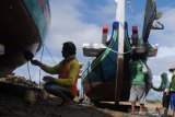 Nelayan mengecat perahu di Pantai Desa Tanjung, Pamekasan, Jawa Timur, Selasa (3/11/2020). Sekitar 50 nelayan di daerah itu mulai mempercantik perahunya untuk persiapan petik laut yang akan dilaksanakan tanggal 6 - 9 November ini. Antara Jatim/Saiful Bahri/zk