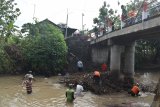 Warga membersihkan sampah yang tersangkut di pilar jembatan sungai di Kabupetan Madiun, Jawa Timur, Selasa (3/11/2020). Kegiatan membersihkan sampah yang terbawa arus sungai dari arah hulu dan tersangkut di pilar jembatan tersebut dimaksudkan untuk mencegah agar jembatan tidak roboh akibat tekanan arus sungai bila terjadi banjir. Antara Jatim/Siswowidodo/zk