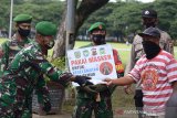 Anggota TNI membawa poster membagikan masker kepada pengunjung di sela kegiatan rapid tes massal di area publik, Lapangan Blang Padang, Banda Aceh, Aceh, Sabtu (7/11/2020). Rapid test massal gratis disertai sosialisasi protokol kesehatan di lokasi bermain ramai pengunjung berlangsung selama dua hari itu bertujuan mencegah penyebaran dan sekaligus menekan peningkatan kasus COVID-19. Antara Aceh/Ampelsa.