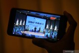 Warga menyaksikan Debat Publik kedua Pemilihan Kepala Daerah (Pilkada) Kota Surabaya melalui ponsel pintar miliknya di Surabaya, Jawa Timur, Rabu (18/11/2020). Debat publik kedua tersebut membahas tema tentang 