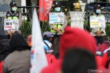 Polisi Wanita (Polwan) membentangkan poster imbauan saat sejumlah buruh berunjuk rasa di Jalan Pahlawan, Surabaya, Jawa Timur, Kamis (19/11/2020). Massa buruh menolak UU Cipta Kerja dan menuntut kenaikan Upah Minimun Kabupaten/Kota tahun 2021 sebesar Rp600.000. Antara Jatim/Didik/Zk