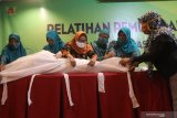 Peserta membalut relawan dengan kain kafan saat pelatihan pemulasaraan jenazah yang diselenggarakan pemerintah daerah Kota Kediri di Kota Kediri, Jawa Timur, Jumat (20/11/2020). Pelatihan yang diikuti oleh perwakilan Gabungan Organisasi Wanita (GOW) tersebut bertujuan memberikan keterampilan pemulasaraan jenazah sesuai dengan syariat Islam dan protokol kesehatan COVID-19. Antara Jatim/Prasetia Fauzani/mas.