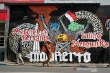 Warga melintas di depan lukisan dinding atau mural di Jalan R Wijaya Kota Mojokerto, Jawa Timur, Minggu (22/11/2020). Mural yang berpesan 