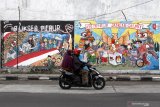 Pengendara melintas di depan mural Pemilu 2020 di kawasan Candi, Sidoarjo, Jawa Timur, Selasa (24/11/2020). Mural tersebut sebagai salah satu bentuk sosialisasi serta menarik keikutsertaan masyarakat untuk menggunakan hak suaranya dalam Pemilu pada 9 Desember mendatang. Antara Jatim/Umarul Faruq/um