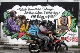 Pengendara melintas di depan mural Pemilu 2020 di kawasan Candi, Sidoarjo, Jawa Timur, Selasa (24/11/2020). Mural tersebut sebagai salah satu bentuk sosialisasi serta menarik keikutsertaan masyarakat untuk menggunakan hak suaranya dalam Pemilu pada 9 Desember mendatang. Antara Jatim/Umarul Faruq/um
