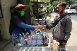 Penjual jamu keliling dengan mengenakan masker melayani pembeli di Tembelang, Kabupaten Jombang, Jawa Timur, Kamis (26/11/2020). Penjual jamu tersebut menerapkan protokol kesehatan saat berjualan keliling. Antara Jatim/Syaiful Arif/Um