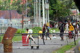 Massa melempar batu ke arah anggota kepolisian saat aksi unjuk rasa di Kota Sorong, Papua Barat, Jumat (27/11/2020). Unjuk rasa yang belum diketahui maksud dan tujuannnya tersebut dibubarkan pihak kepolisian karena menyebabkan keramaian di tengah pandemi COVID-19 dan berlangsung ricuh sehingga mengakibatkan empat orang anggota polisi dan satu orang jurnalis terluka. ANTARA FOTO/Olha Mulalinda/wsj. 