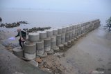 Warga berjalan di atas tangkis laut (tanggul penahan ombak) yang baru selesai dibangun di kawasan Pantai Wisata Talang Siring, Pamekasan, Jawa Timur, Sabtu (28/11/2020). Proyek penyelamatan pantai dari abrasi itu, direncanakan  berkelanjutan. Antara Jatim/Saiful Bahri/mas.