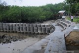 Warga berjalan di dekat tangkis laut (tanggul penahan ombak) yang baru selesai dibangun di kawasan Pantai Wisata Talang Siring, Pamekasan, Jawa Timur, Sabtu (28/11/2020). Proyek penyelamatan pantai dari abrasi itu, direncanakan  berkelanjutan. Antara Jatim/Saiful Bahri/mas.