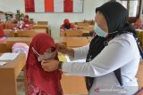 Guru membantu memakaikan masker kepada murid di salah satu Sekolah Dasar Negeri, Desa Garut, Kecamatan Darul Imara, Kabupaten Aceh Besar, Aceh, Selasa (2/12/2020). Pemerintah Aceh meluncurkan Gerakan Masker Sekolah (Gemas) dalam mencegah penyebaran COVID-19 dengan menyasar sebanyak 1,08 juta pelajar dari 6.783 sekolah di Aceh, namun masker yang dibagikan kepada murid sekolah dasar itu ukuran dewasa dan tidak sesuai dengan ukuran anak sekolah dasar, sehingga tidak dapat dimanfaatkan. Antara Aceh/Ampelsa.