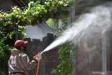 Petugas Palang Merah Indonesia (PMI) menyemprotkan cairan disinfektan di lingkungan sekitar rumah warga yang meninggal akibat positif COVID-19 di Kota Madiun, Jawa Timur, Sabtu (5/12/2020). Penyemprotan tersebut dimaksudkan untuk pencegahan penularan COVID-19 di Kota Madiun. Antara Jatim/Siswowidodo/Um