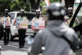 Petugas kepolisian melakukan sosialisasi kepada pengendara yang melintas di jalan Raya Waru, perbatasan Surabaya - Sidoarjo, Jawa Timur, Selasa (8/12/2020). Sosialisasi tersebut untuk mengajak dan mengimbau masyarakat menggunakan hak suaranya dalam Pilkada serentak 2020 dengan tetap menerapkan protokol kesehatan. Antara Jatim/Umarul Faruq/Um