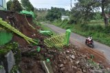 Pengendara melintas di dekat longsoran material pagar dan halaman SMPN 1 Kare, Kabupaten Madiun, Jawa Timur, Senin (14/12/2020). Sebagian halaman dan pagar sekolah tersebut longsor akibat hujan deras yang terjadi Minggu (13/12). Antara Jatim/Siswowidodo/Um