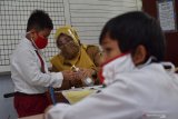 Murid SD mengikuti simulasi belajar tatap muka dengan menerapkan protokol kesehatan pencegahan penularan COVID-19 di SDN 1 Kare, Kabupaten Madiun, Jawa Timur, Senin (14/12/2020). Simulasi tersebut sebagai persiapan pelaksanaan belajar secara tatap muka pada masa pandemi COVID-19 yang akan dimulai 4 Januari 2021. Antara Jatim/Siswowidodo/Um