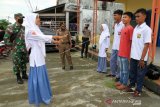 Sejumlah pelajar menyanyikan lagu Indonesia Raya saat terjaring razia pelanggar protokol kesehatan di Desa Gampa, Kecamatan Johan Pahlawan, Aceh Barat, Aceh, Selasa (15/12/2020). Razia penerapan dan penegakan hukum protokol kesehatan yang digelar secara rutin tersebut sebagai upaya pencegahan dan pengedalian penyebaran COVID-19 di Kabupaten setempat, dan pelanggar terbanyak didominasi remaja, pelajar dan Pegawai Negeri Sipil (PNS) dengan pelanggaran utama tidak menggunakan masker. ANTARA FOTO/Syifa Yulinnas/wsj.