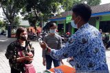 Petugas melakukan pengecekan suhu tubuh pada warga saat digelar operasi pasar murni Kota Kediri Jawa Timur,  Kamis (17/12/2020). Operasi pasar tersebut guna menstabilkan harga jelang perayaan Natal 2020 dan Tahun Baru 2021. Antara Jatim/ Asmaul Chusna