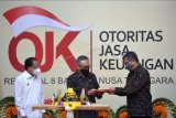 Ketua Dewan Komisioner Otoritas Jasa Keuangan (OJK) Wimboh Santoso (tengah) menyerahkan potongan nasi tumpeng kepada Kepala OJK Regional 8 Giri Tribroto (kanan) disaksikan Gubernur Bali Wayan Koster (kiri) saat peresmian gedung Kantor OJK Regional 8 di Denpasar, Bali, Senin (21/12/2020). Gedung Kantor OJK Regional 8 Bali dan Nusa Tenggara tersebut diharapkan dapat meningkatkan peran dan kontribusi OJK dalam meningkatkan pembangunan di daerah melalui hadirnya sektor keuangan. ANTARA FOTO/Fikri Yusuf/nym.