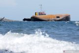 Kapal tongkang terbalik di pantai Bangsring, Banyuwangi, Jawa Timur, Rabu (23/12/2020). Kapal Tongkang Tan 11 bermuatan 7.500 ton klinker yang berlayar dari Pelabuhan Tarjun-Kalimantan Selatan menuju Pelabuhan Tanjungwangi Banyuwangi itu terbalik saat akan sandar. Tidak ada korban dalam kejadian tersebut. Antara Jatim/Budi Candra Setya/Um