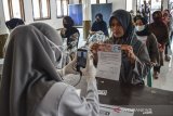 Petugas memotret identitas penerima bantuan sebagai tanda bukti saat penyaluran bantuan sosial (bansos) di Kantor Desa Sindangherang, Kabupaten Ciamis, Jawa Barat, Kamis (24/12/2020). Pemerintah Provinsi Jabar menyalurkan bantuan sosial (bansos) tahap empat senilai Rp100 ribu bagi warga yang berpenghasilan rendah, termasuk warga miskin baru akibat pandemi COVID-19, dengan total penerima bansos sebanyak 1,9 juta Keluarga Rumah Tangga Sasaran (KRTS). ANTARA JABAR/Adeng Bustomi/agr