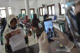 Petugas memotret identitas penerima bantuan sebagai tanda bukti saat penyaluran bantuan sosial (bansos) di Kantor Desa Sindangherang, Kabupaten Ciamis, Jawa Barat, Kamis (24/12/2020). Pemerintah Provinsi Jabar menyalurkan bantuan sosial (bansos) tahap empat senilai Rp100 ribu bagi warga yang berpenghasilan rendah, termasuk warga miskin baru akibat pandemi COVID-19, dengan total penerima bansos sebanyak 1,9 juta Keluarga Rumah Tangga Sasaran (KRTS). ANTARA JABAR/Adeng Bustomi/agr