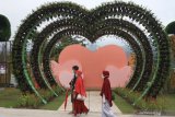 Pengunjung melintas di depan dekorasi bunga berbentuk cinta di wahana wisata Batu Love Garden, Batu, Jawa Timur, Sabtu (26/12/2020). Wahana wisata berupa taman bunga seluas tujuh hektare tersebut memadukan konsep inovasi taman dinding atau vertikal garden dengan menonjolkan keindahan bunga sebagai daya tarik wisata. Antara Jatim/Ari Bowo Sucipto/mas.