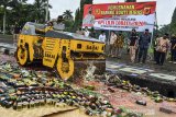 Petugas menggunakan alat berat memusnahkan barang bukti minuman keras hasil sitaan cipta kondisi operasi lilin lodaya di Alun-alun Ciamis, Jawa Barat, Rabu (30/12/2020). Sebanyak 3.775 botol miras dan 665 liter miras oplosan dimusnahkan untuk mencegah penyakit masyarkat jelang perayaan malam tahun baru. ANTARA JABAR/Adeng Bustomi/agr