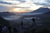 Wisatawan menyaksikan matahari terbit pertama tahun 2021 di Desa Pinggan, Kintamani, Bangli, Bali, Jumat (1/1/2021). Kawasan wisata alam dengan pemandangan Gunung Agung, Gunung Batur dan Gunung Abang tersebut menjadi salah satu lokasi di Pulau Dewata yang dikunjungi wisatawan untuk menyaksikan matahari terbit pertama tahun 2021. ANTARA FOTO/Fikri Yusuf/nym.