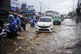 Kendaraan menerjang air yang menggenangi Jalan Raya Cinunuk, Kabupaten Bandung, Jawa Barat, Senin (4/1/2021). Genangan air setinggi 10 hingga 50 sentimeter menggenangi Jalan Nasional menuju Sumedang, Tasik dan Garut akibat drainase yang buruk sehingga tidak dapat menampung debit air secara maksimal saat hujan lebat mengguyur kawasan Bandung Raya. ANTARA JABAR/Raisan Al Farisi/agr