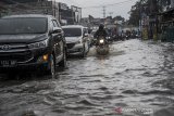 Kendaraan menerjang air yang menggenangi Jalan Raya Cinunuk, Kabupaten Bandung, Jawa Barat, Senin (4/1/2021). Genangan air setinggi 10 hingga 50 sentimeter menggenangi Jalan Nasional menuju Sumedang, Tasik dan Garut akibat drainase yang buruk sehingga tidak dapat menampung debit air secara maksimal saat hujan lebat mengguyur kawasan Bandung Raya. ANTARA JABAR/Raisan Al Farisi/agr