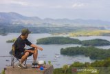 Wisatawan menikmati keindahan waduk riam kanan dari puncak Bukit Batas di Kabupaten Banjar, Kalimantan Selatan, Senin (4/1/2021). Wisata puncak Bukit Batas yang menawarkan panorama gugusan pulau serta hamparan pegunungan meratus yang berada di Waduk Riam Kanan tersebut menjadi salah satu potensi wisata alam Kalimantan Selatan yang dapat menarik minat wisatawan untuk berkunjung ke Kalsel. Foto Antaranews Kalsel/Bayu Pratama S.