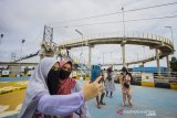 Pengunjung berfoto saat mengunjungi Jembatan Antasan Bromo di Banjarmasin, Kalimantan Selatan, Senin (4/1/2021). Sejumlah warga berkunjung ke Jembatan Antasan Bromo di Banjarmasin, Kalimantan Selatan, Senin (4/1/2021).  Pemerintah Kota Banjarmasin meresmikan kawasan ekowisata, Jembatan Antasan Bromo dengan panjang 168 meter dan lebar dua meter, selain berfungsi sebagai infrastruktur penghubung antar kampung tersebut juga menjadi salah satu ikon Kota dan tempat wisata baru Kota Banjarmasin. Foto Antaranews Kalsel/Bayu Pratama S.