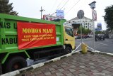 Pengendara melintasi truk pengangkut sampah yang parkir di depan Pendapa Bupati Jember, Jawa Timur, Senin (4/1/2021). Puluhan truk pengangut sampah di Jember mogok beroperasi karena tidak ada anggaran operasional bahan bakar minyak (BBM). Antara Jatim/Seno/zk