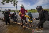 Warga menggunakan titian kayu yang dibuat warga setempat untuk melintasi Jalan Martapura lama yang terendam banjir di Desa Sungai Rangas Ulu, Kabupaten Banjar, Kalimantan Selatan, Rabu (6/1/2021). Menurut Badan Penanggulangan Bencana Daerah (BPBD) Kabupaten Banjar, banjir setinggi lima hingga satu meter yang melanda pemukiman di sejumlah desa di Kabupaten Banjar tersebut dipicu oleh hujan dengan intensitas tinggi sehingga menyebabkan debit air sungai Martapura meluap. Foto Antaranews Kalsel/Bayu Pratama S.