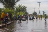 Warga menggunakan titian kayu yang dibuat warga setempat untuk melintasi Jalan Martapura lama yang terendam banjir di Desa Sungai Rangas Ulu, Kabupaten Banjar, Kalimantan Selatan, Rabu (6/1/2021). Menurut Badan Penanggulangan Bencana Daerah (BPBD) Kabupaten Banjar, banjir setinggi lima hingga satu meter yang melanda pemukiman di sejumlah desa di Kabupaten Banjar tersebut dipicu oleh hujan dengan intensitas tinggi sehingga menyebabkan debit air sungai Martapura meluap. Foto Antaranews Kalsel/Bayu Pratama S.